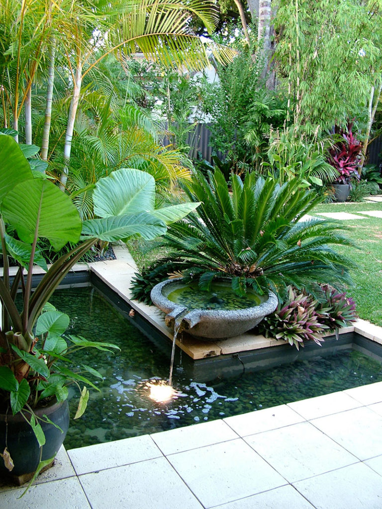 Lavastone bowl overflowing to water reservoir in nedlands garden with cycads and tropical plants
